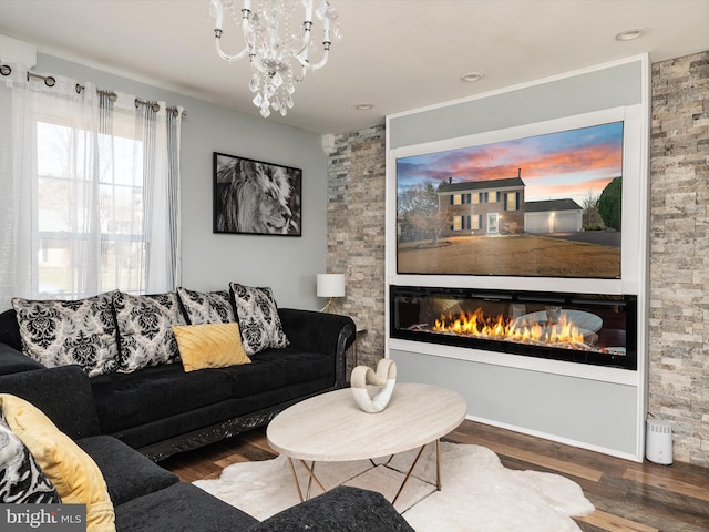 living area with wood finished floors, an inviting chandelier, and a glass covered fireplace