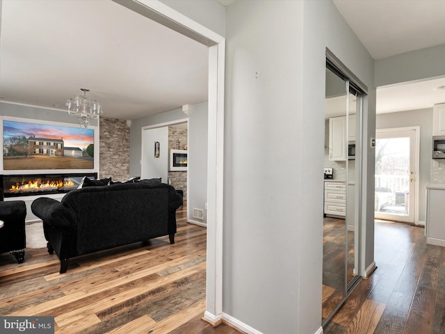 hall with visible vents, baseboards, hardwood / wood-style floors, and a chandelier