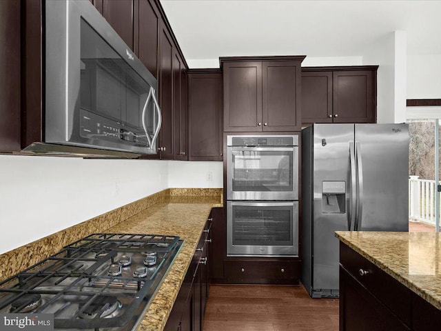 kitchen featuring stainless steel appliances, light stone counters, dark wood-type flooring, and dark brown cabinets