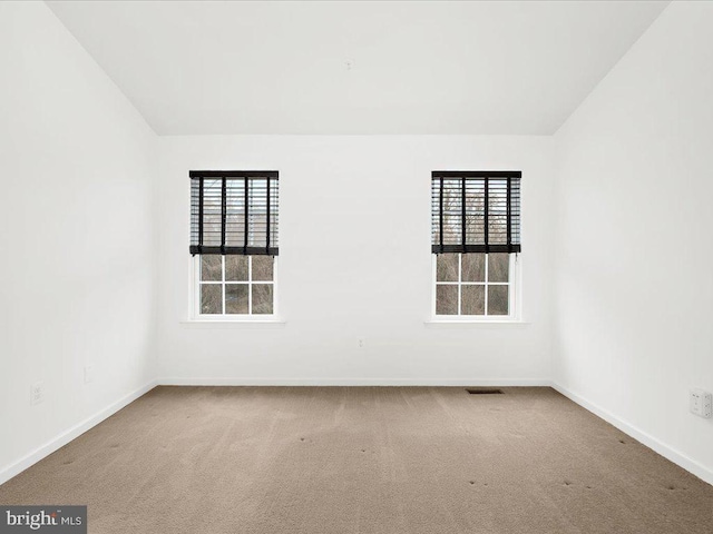 carpeted empty room featuring lofted ceiling, visible vents, and baseboards