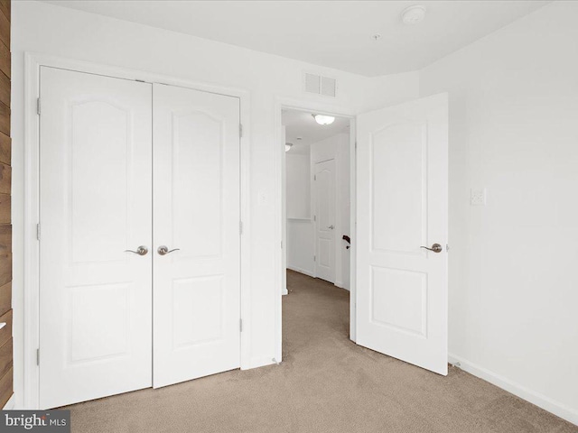 unfurnished bedroom featuring light colored carpet, a closet, visible vents, and baseboards