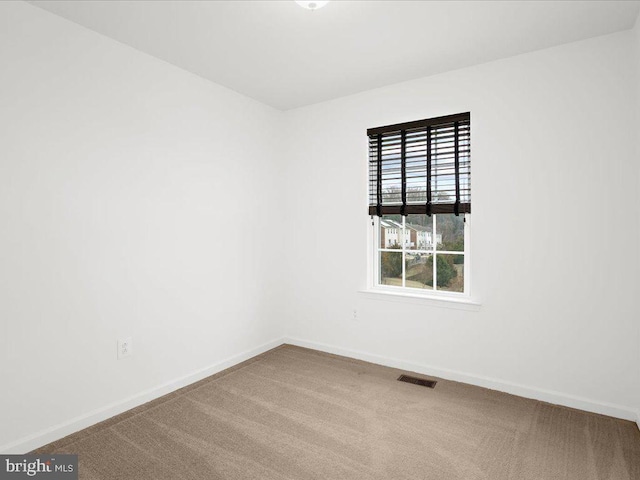 carpeted spare room featuring visible vents and baseboards