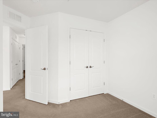 unfurnished bedroom featuring carpet, a closet, visible vents, and baseboards