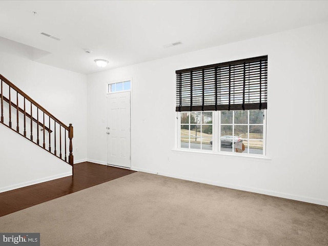 entryway with carpet floors, visible vents, stairway, and baseboards