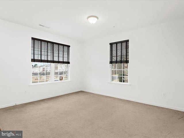 carpeted empty room featuring baseboards and visible vents