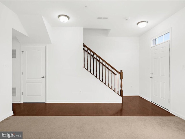 entrance foyer with wood finished floors, carpet flooring, and stairs