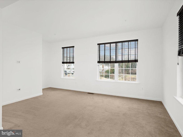 spare room featuring carpet floors, visible vents, and baseboards