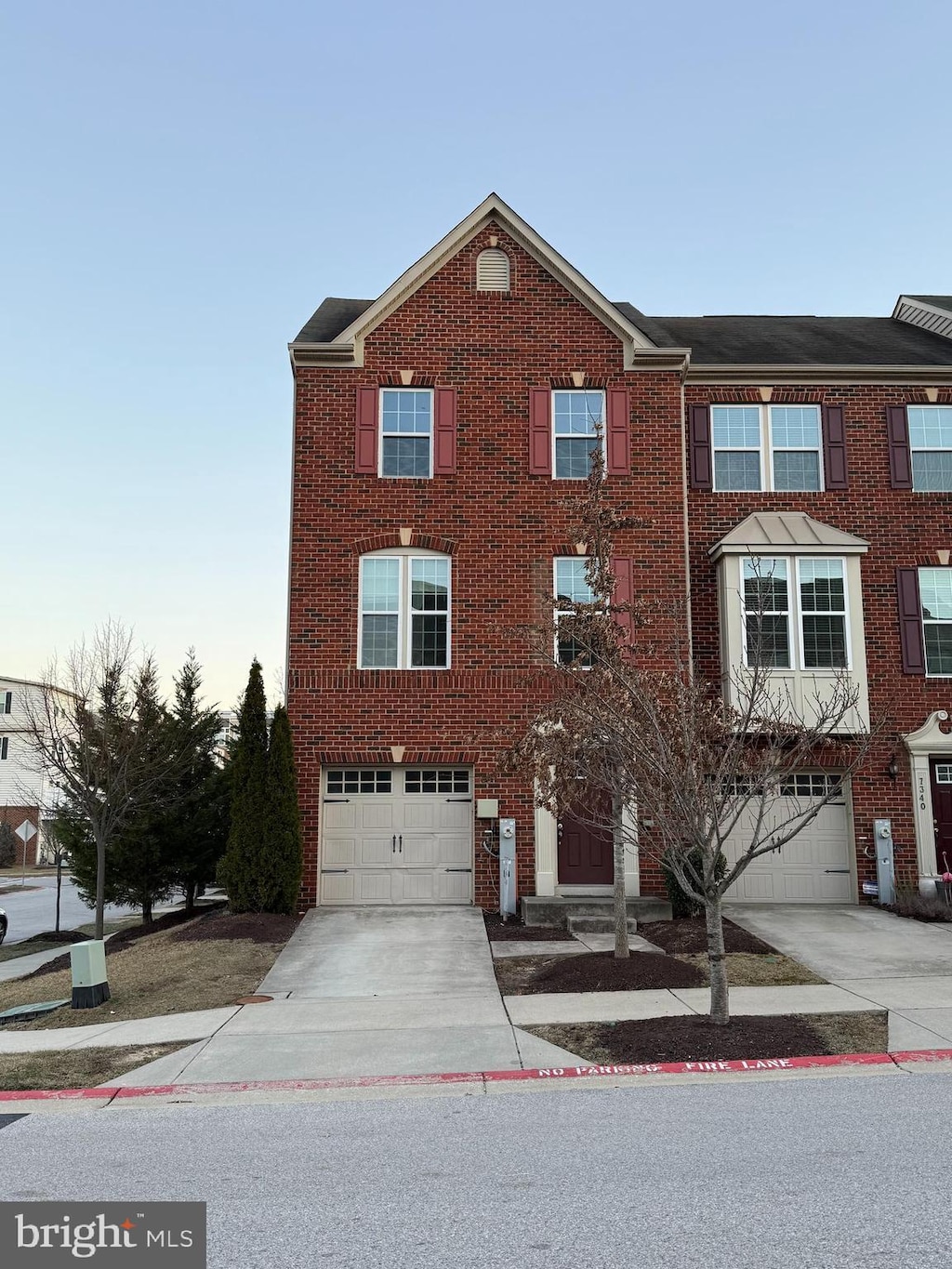 multi unit property featuring a garage, brick siding, and driveway