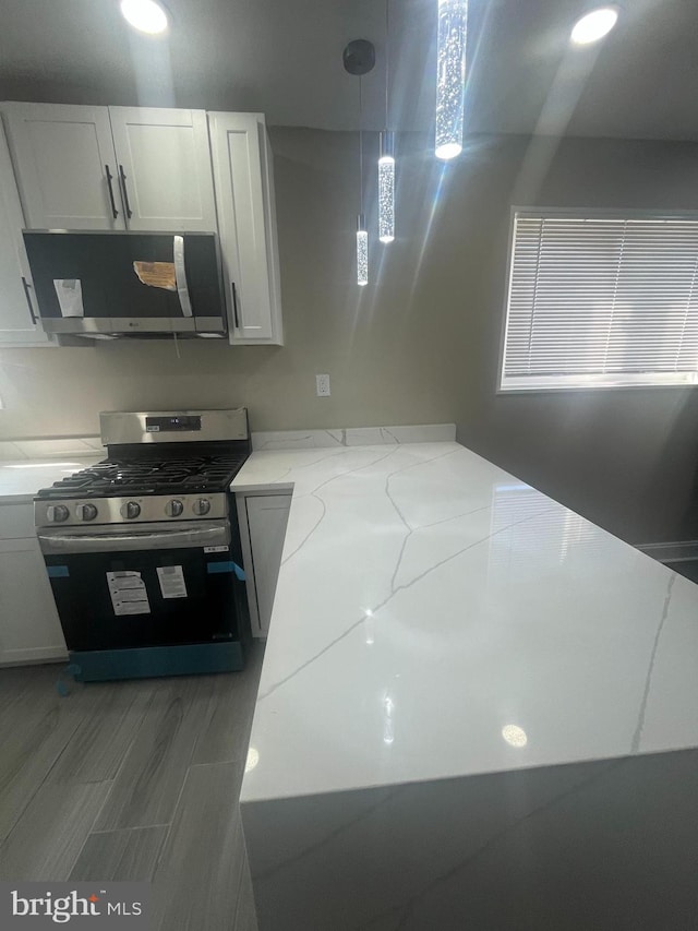 kitchen featuring appliances with stainless steel finishes, white cabinets, hanging light fixtures, and light stone countertops