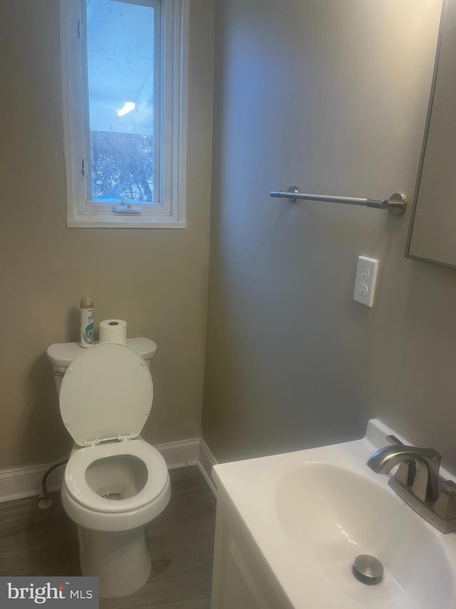 bathroom with wood finished floors, a sink, toilet, and baseboards