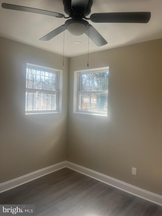 empty room featuring dark wood-style floors, baseboards, and a ceiling fan