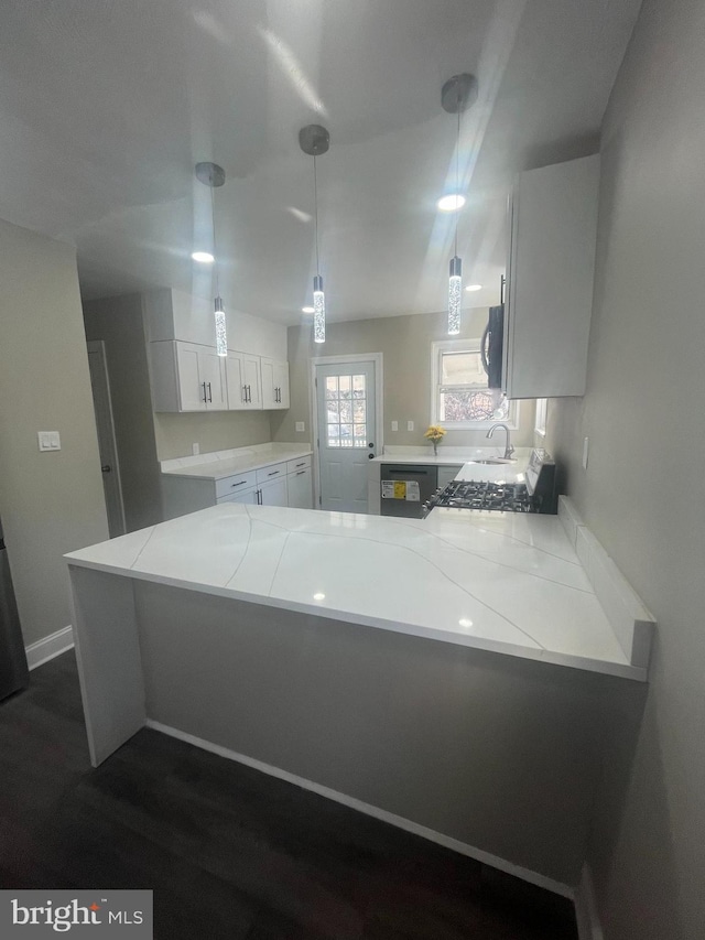 kitchen with light countertops, hanging light fixtures, white cabinets, a sink, and a peninsula