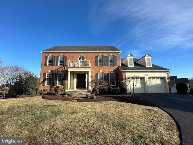 view of front of home featuring a garage, driveway, brick siding, and a balcony