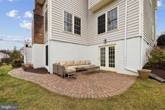 back of house featuring french doors, brick siding, a patio, a lawn, and an outdoor living space