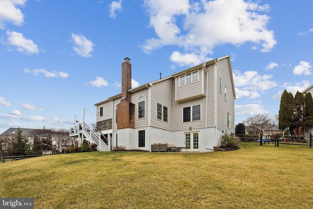 back of house featuring fence, stairs, french doors, a lawn, and a chimney