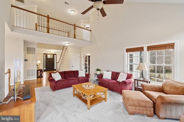 living area featuring visible vents, stairway, and wood finished floors