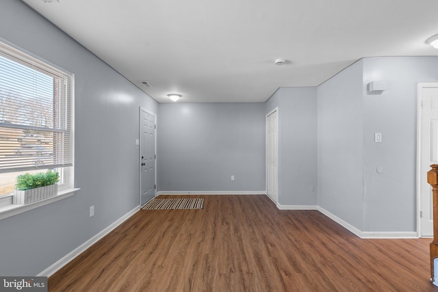 spare room with wood finished floors, visible vents, and baseboards