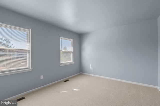 empty room with visible vents, light carpet, and baseboards