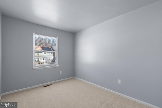 empty room featuring visible vents, baseboards, and carpet flooring