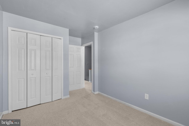 unfurnished bedroom featuring carpet, baseboards, and a closet