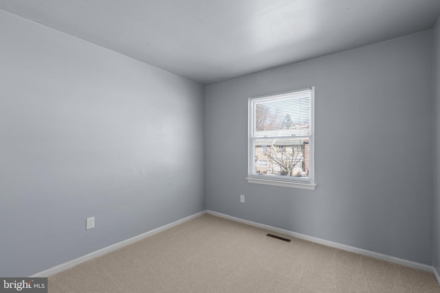 spare room featuring light carpet, visible vents, and baseboards