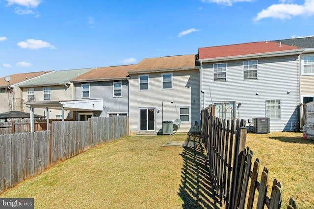 back of house featuring central air condition unit, a residential view, and a yard