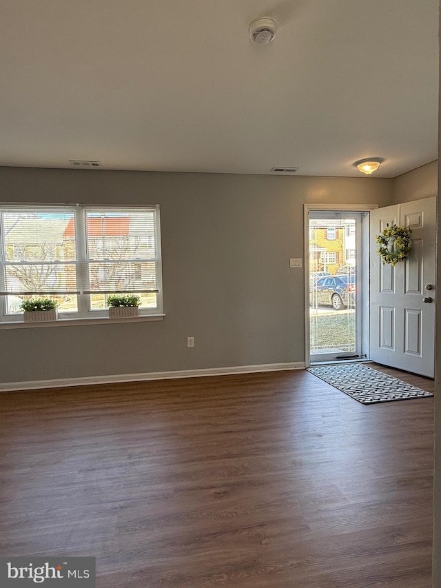 interior space with baseboards, visible vents, and dark wood-style flooring