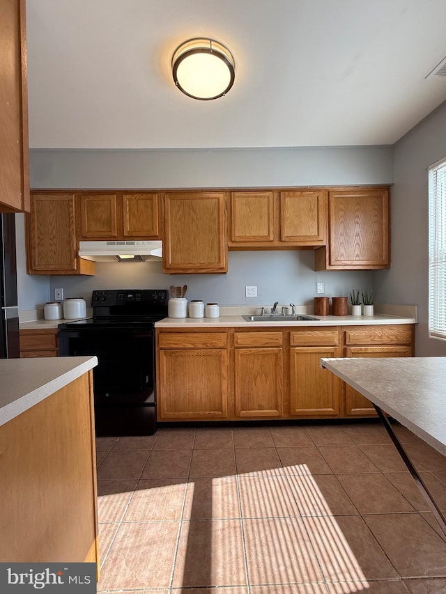 kitchen with under cabinet range hood, black range with electric cooktop, light countertops, and light tile patterned flooring