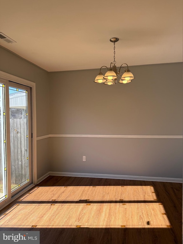 unfurnished dining area featuring baseboards, visible vents, a chandelier, and wood finished floors