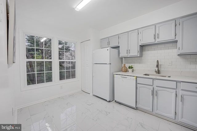 kitchen with marble finish floor, tasteful backsplash, light countertops, a sink, and white appliances