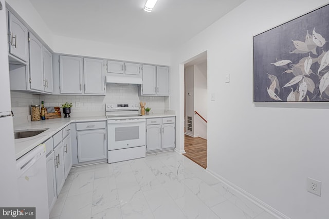 kitchen featuring white appliances, decorative backsplash, marble finish floor, light countertops, and under cabinet range hood