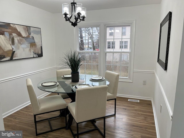 dining room featuring an inviting chandelier, baseboards, visible vents, and wood finished floors