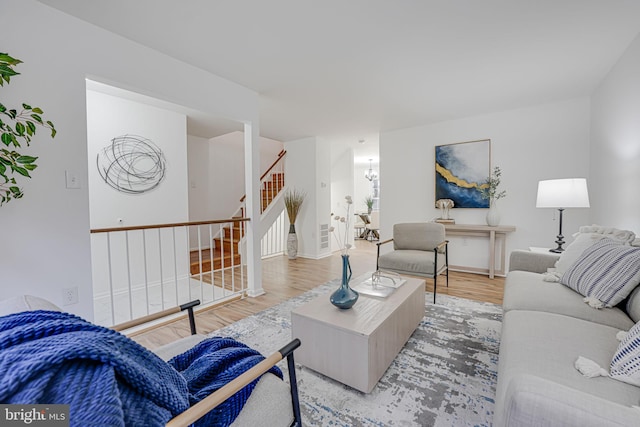 living room featuring baseboards, stairway, a chandelier, and wood finished floors