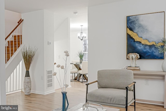 living area featuring visible vents, baseboards, stairway, wood finished floors, and a notable chandelier