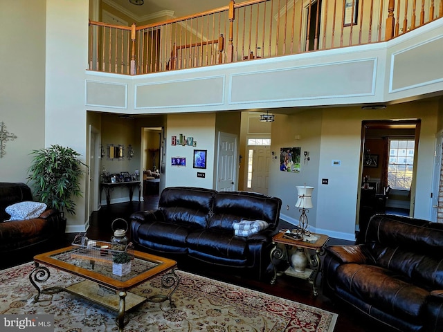 living room with a towering ceiling, baseboards, and wood finished floors