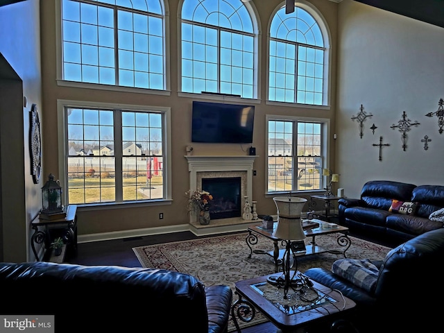 living room featuring a towering ceiling, a fireplace, and baseboards