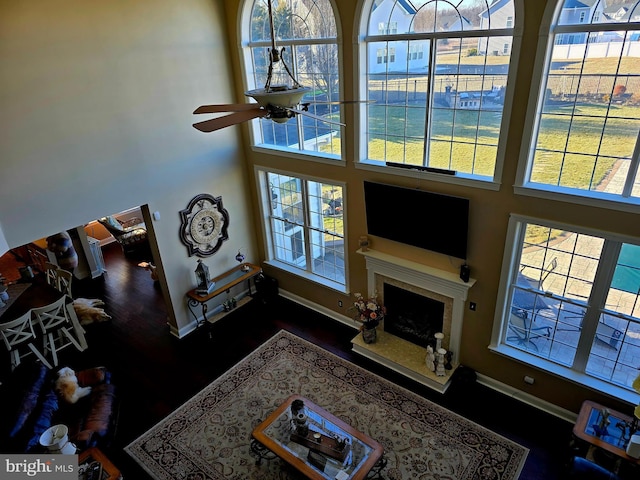 living room featuring a high ceiling, baseboards, a ceiling fan, and a high end fireplace