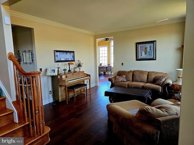 living room featuring dark wood-style flooring, crown molding, baseboards, and stairs