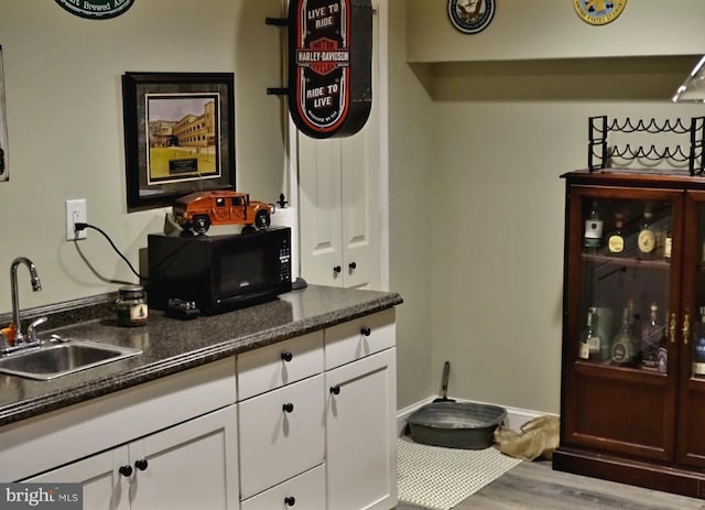 interior space featuring black microwave, wood finished floors, a sink, and baseboards