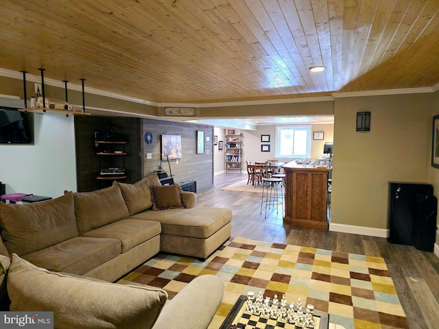 living area featuring baseboards, wood ceiling, ornamental molding, and wood finished floors