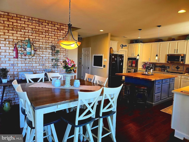 dining space with dark wood-style floors, brick wall, and recessed lighting