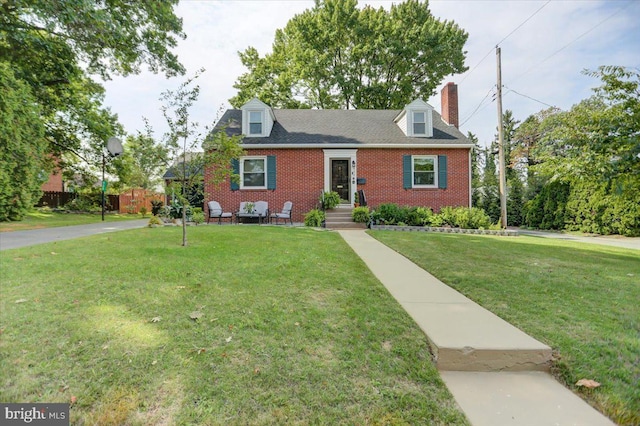 cape cod home featuring brick siding and a front yard