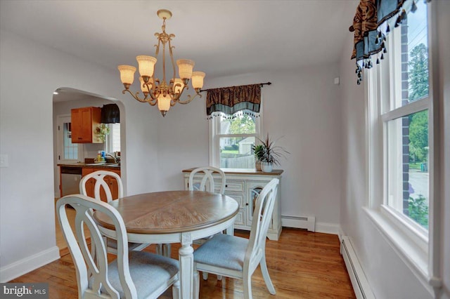 dining room featuring arched walkways, a baseboard radiator, and light wood-style flooring