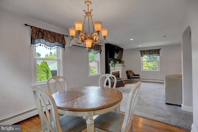 dining area with arched walkways, a fireplace, a baseboard radiator, an inviting chandelier, and wood finished floors