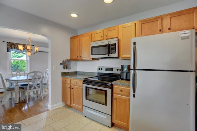 kitchen featuring arched walkways, a chandelier, light tile patterned flooring, recessed lighting, and appliances with stainless steel finishes