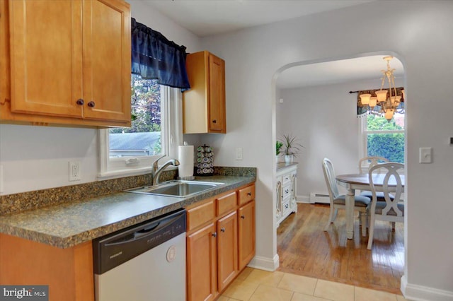 kitchen with arched walkways, light tile patterned floors, dark countertops, a sink, and dishwashing machine