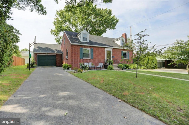 new england style home with aphalt driveway, brick siding, an attached garage, fence, and a front lawn