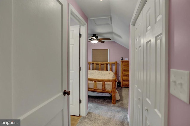 corridor featuring vaulted ceiling, light carpet, and attic access