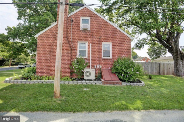 view of side of property with ac unit, brick siding, a yard, a chimney, and fence