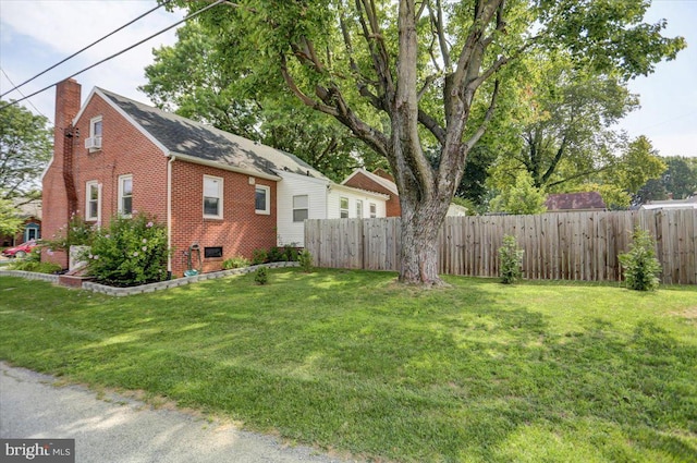 exterior space featuring a yard, brick siding, a chimney, and fence